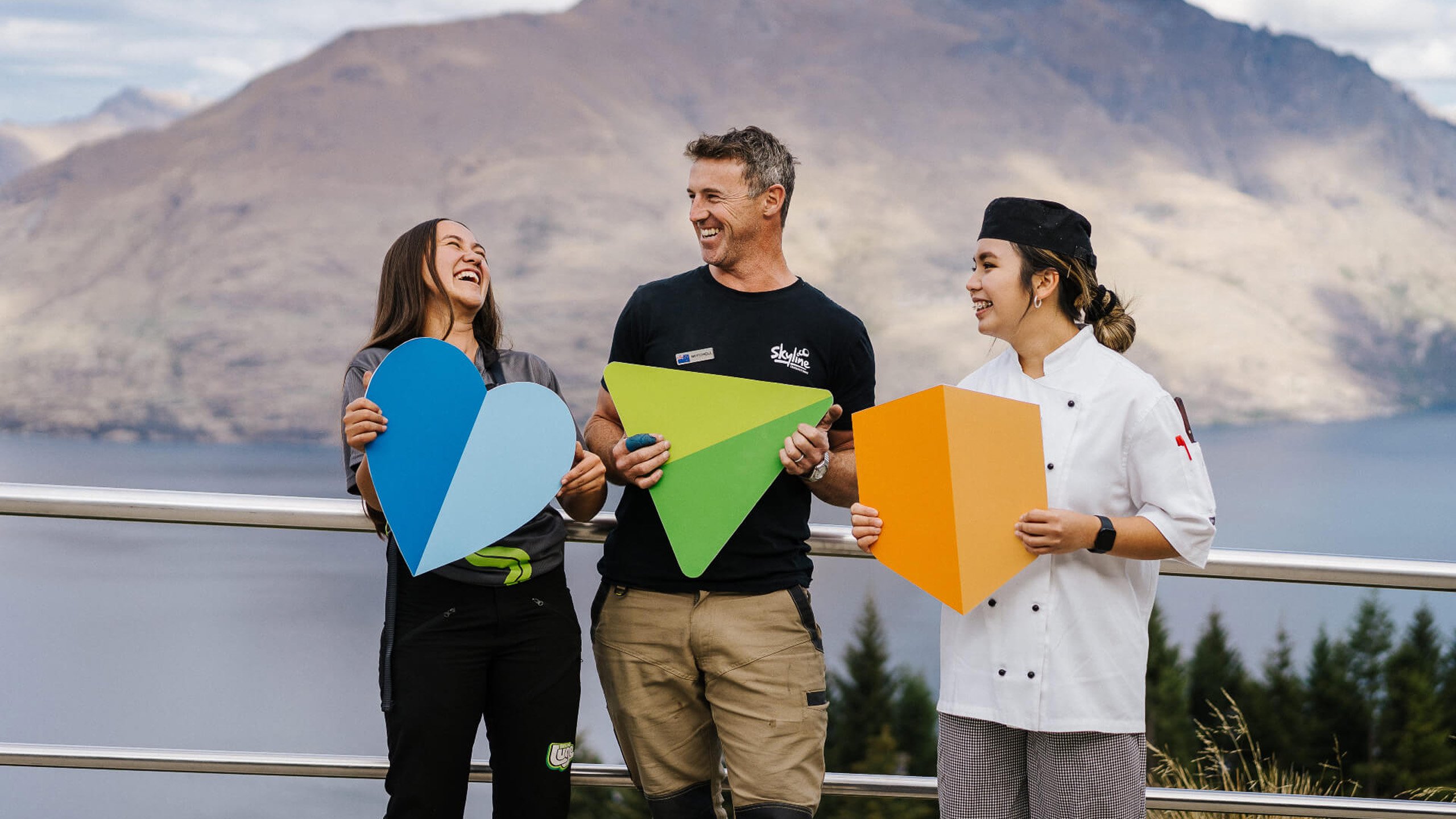 Three workers, two female, 1 male standing around having a great time at work
