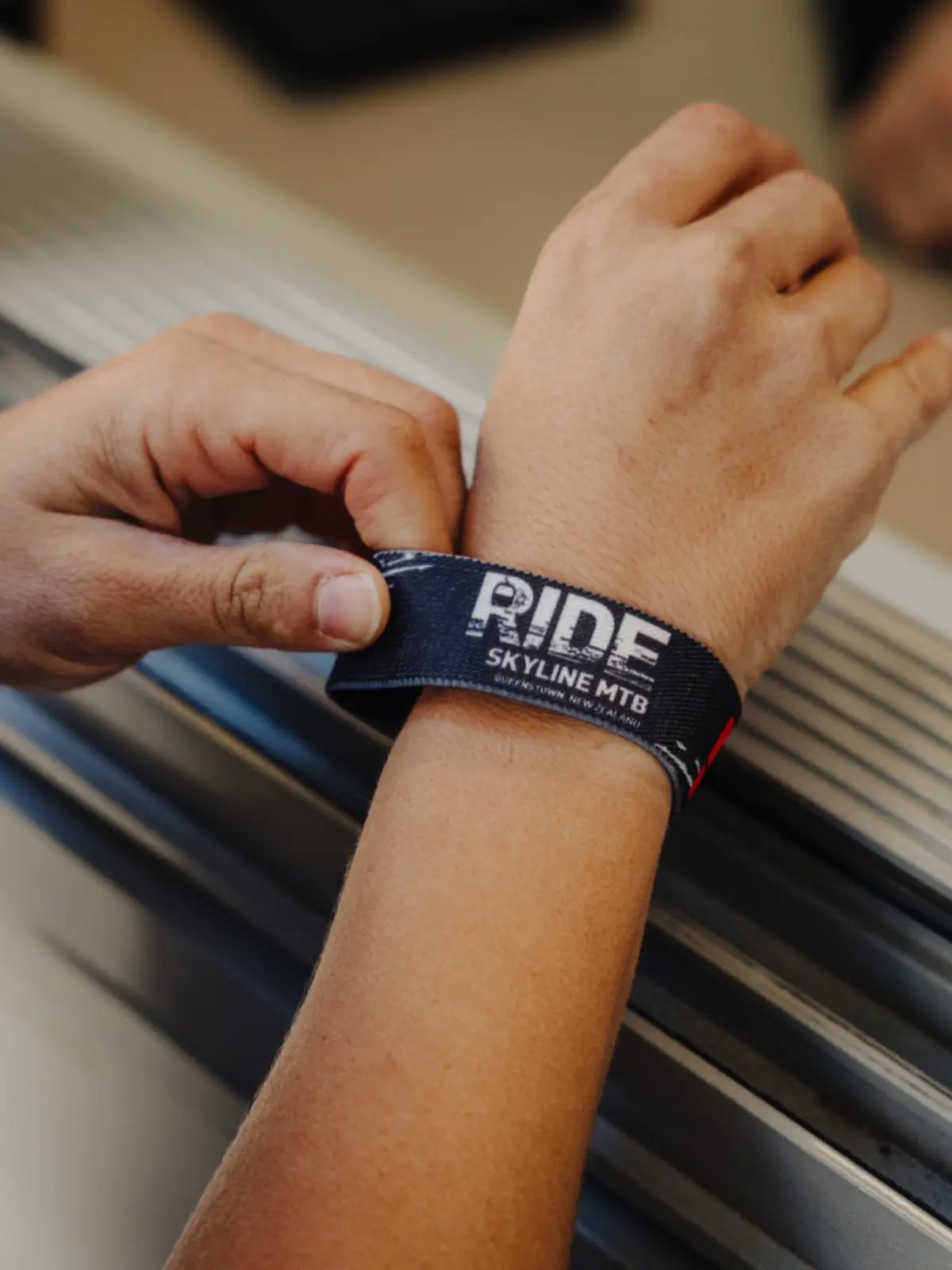 Guest receiving a Skyline Queenstown MTB Season Pass wristband before accessing gondola uplifts and the Ben Lomond mountain bike trails.