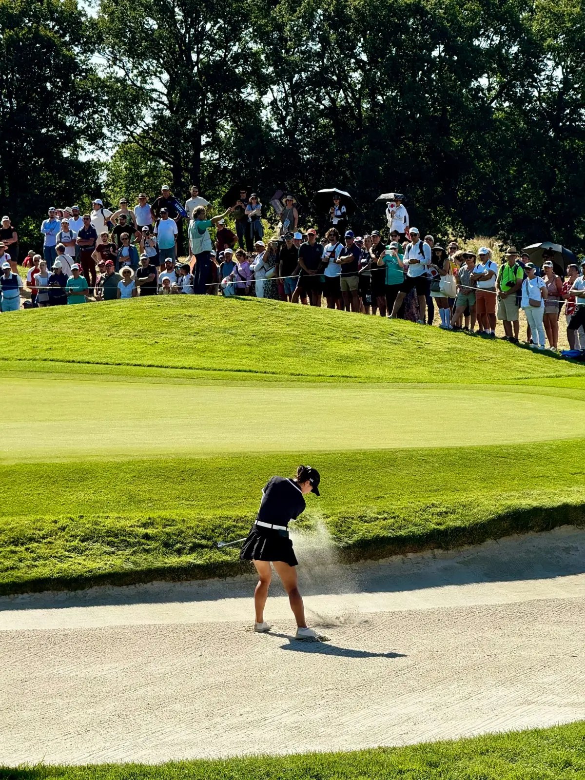 Golfer playing a bunker shot as spectators watch during the Skyline Charity Golf Classic in Queenstown.
