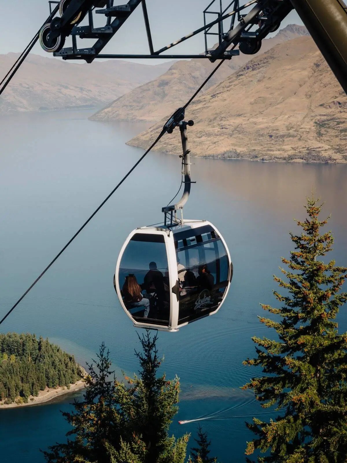 Guests riding the Skyline Queenstown Gondola above Lake Wakatipu, surrounded by mountain views and native forest overlooking Queenstown.