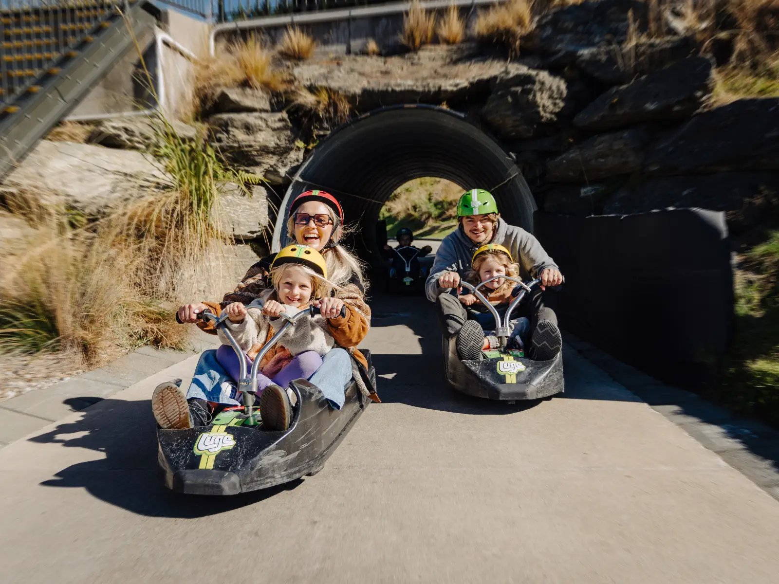 Family riding the Skyline Queenstown Luge together through a tunnel on the track