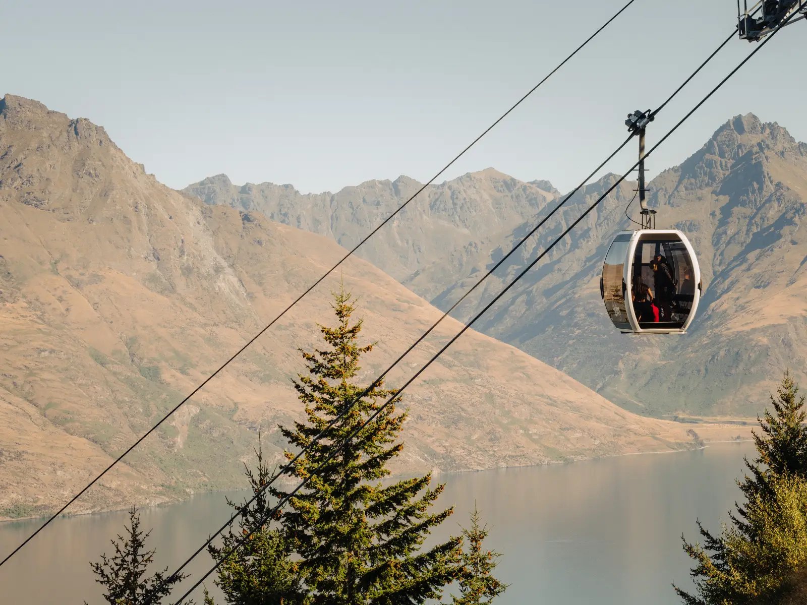 Skyline Queenstown Gondola cabin travelling above Lake Wakatipu with mountain scenery in the background