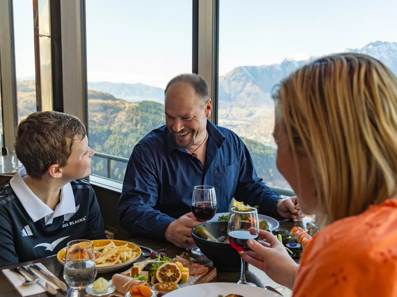 Family enjoying a meal at Stratosfare Restaurant at Skyline Queenstown with panoramic mountain views