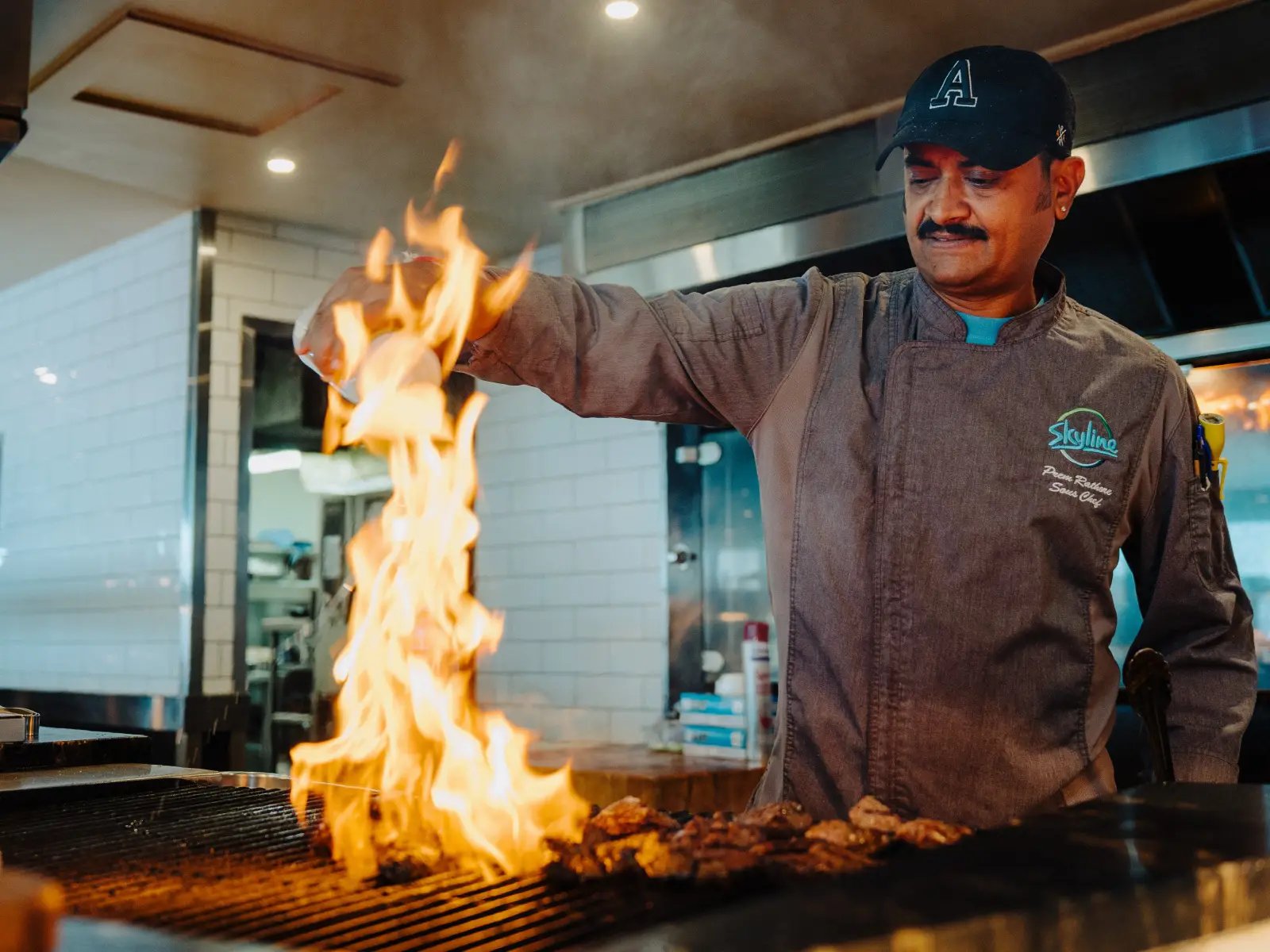Stratosfare Restaurant chef flame grilling meat in the open kitchen at Skyline Queenstown
