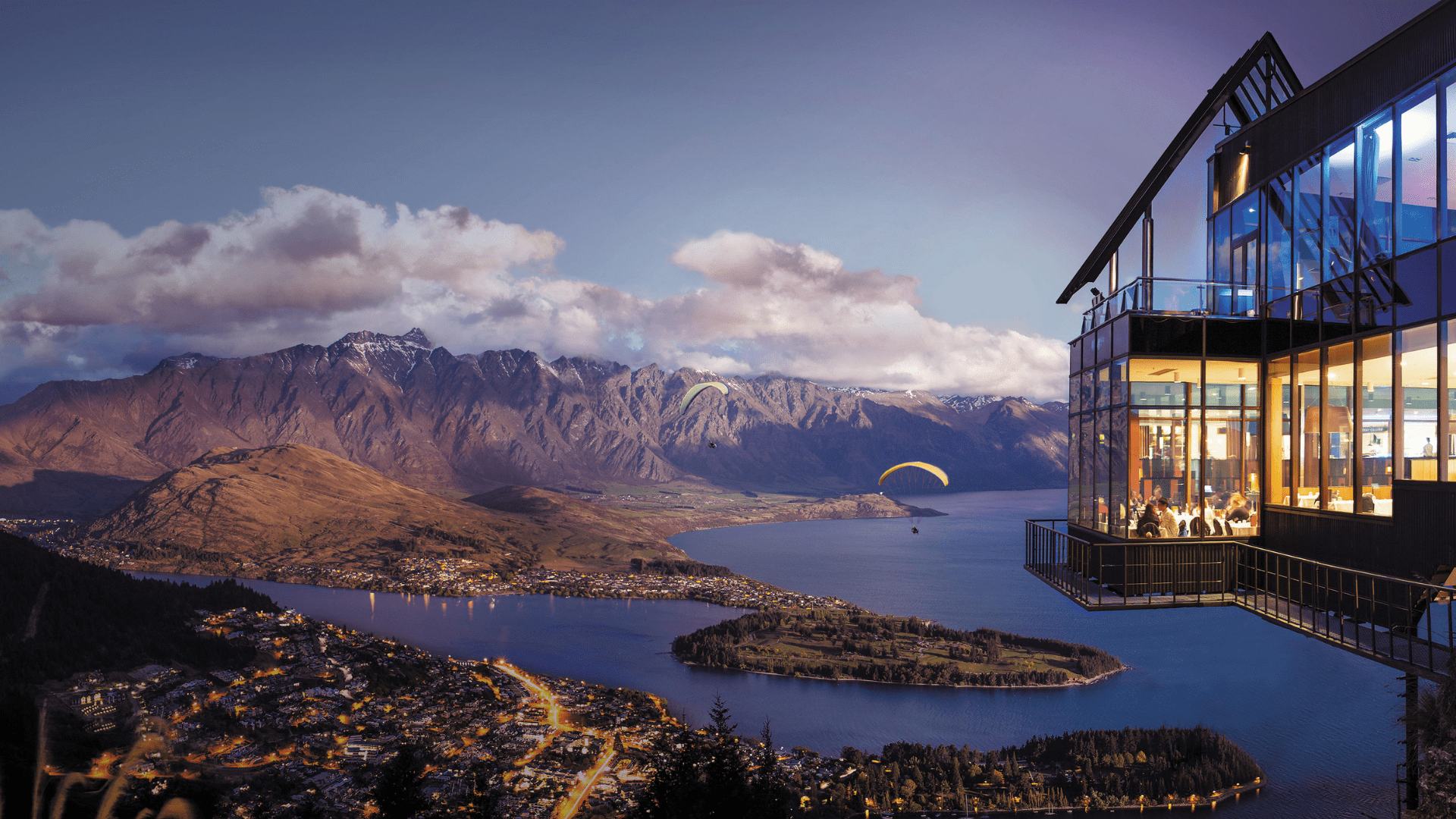 A stunning view of Skyline Queenstown at sunset with views of The Remarkables behind Queenstown.