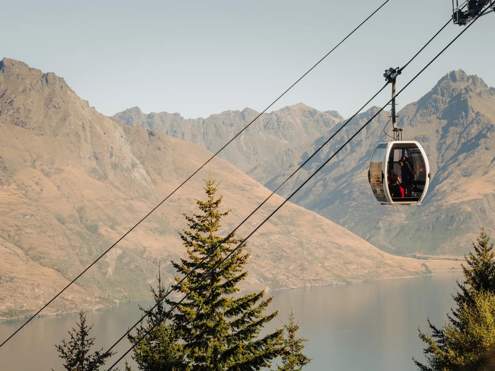 Skyline Queenstown Gondola cabin travelling above Lake Wakatipu with mountain scenery in the background