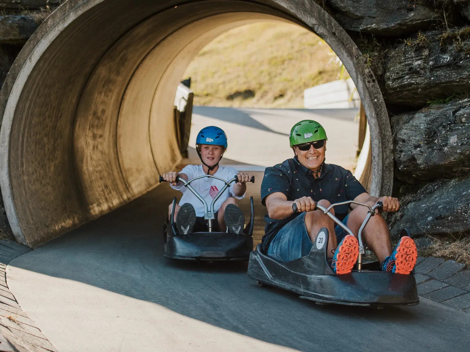 Adult and child riding the Skyline Queenstown Luge through a tunnel on the track