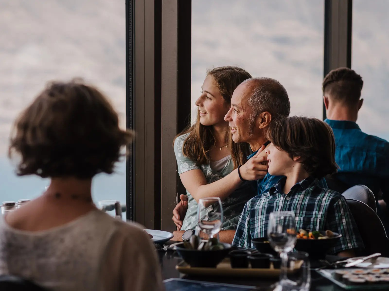 Family enjoying a meal at Stratosfare Restaurant at Skyline Queenstown while looking out over the surrounding landscape