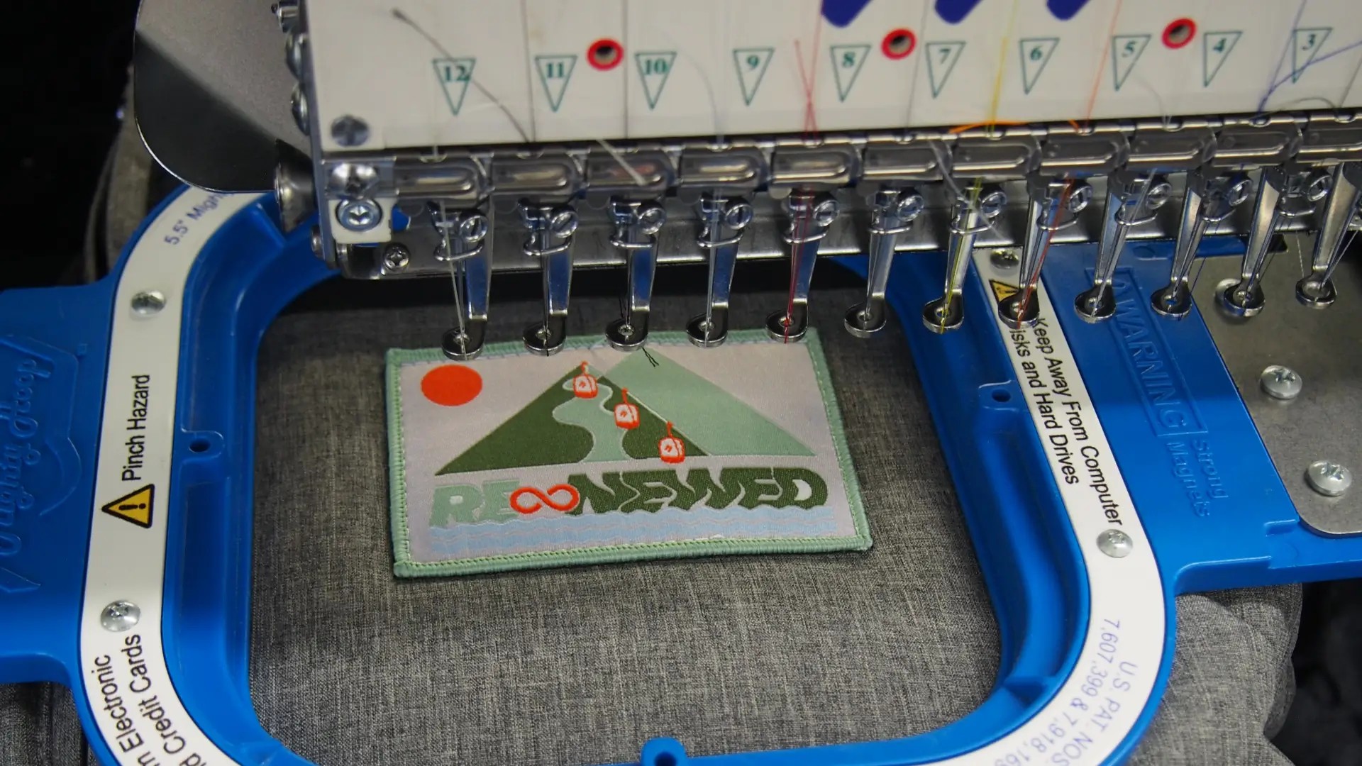 Close-up of embroidery machine stitching a patch over an old Skyline uniform logo to reduce textile waste