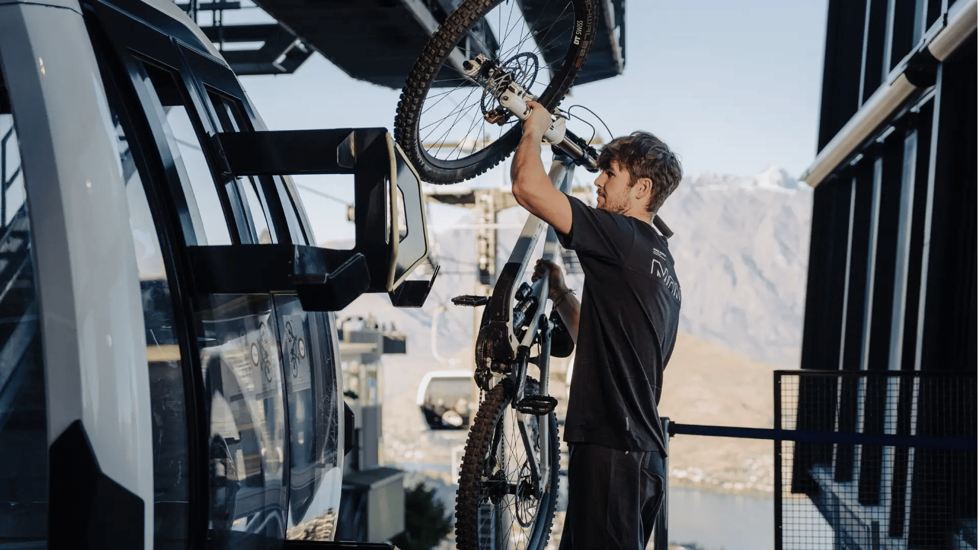 Staff member loading a mountain bike onto the Skyline Queenstown gondola for uplift access to the Ben Lomond mountain bike trails.