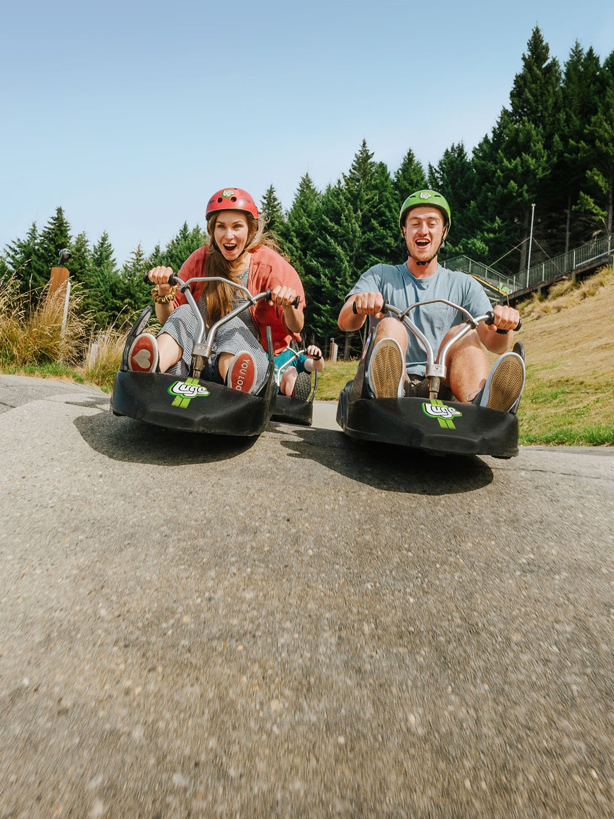 Two people going down the luge track close up showing the track and getting some air
