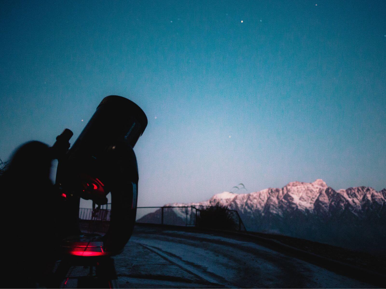 A telescope pointed out towards the sky at twilight